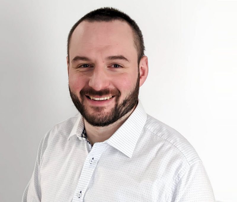 Professional wearing a white polo and smiling at the camera