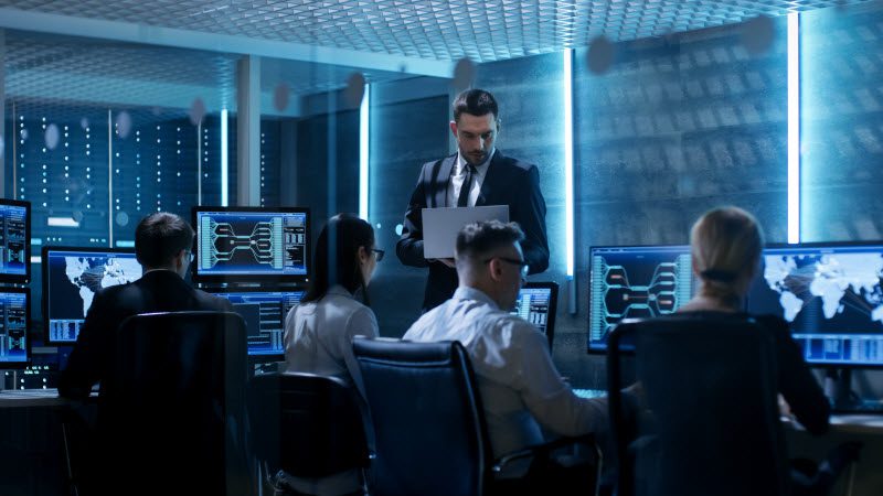 Professional IT Engineers Working in System Control Center Full of Monitors and Servers