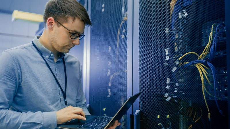 Data Center IT Engineer Stands Before Working Server Rack